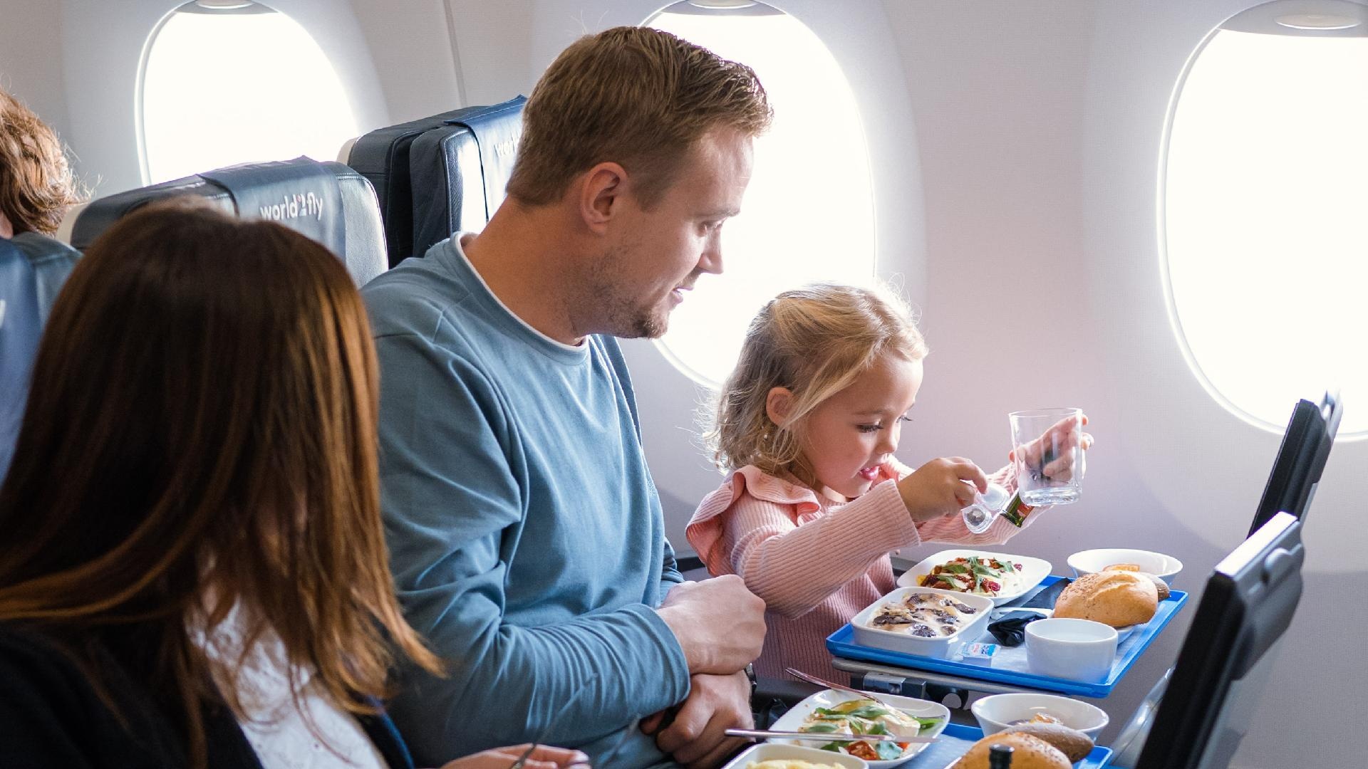 padre madre e hija almorzando a bordo de un avión de world2fly, viaje en familia