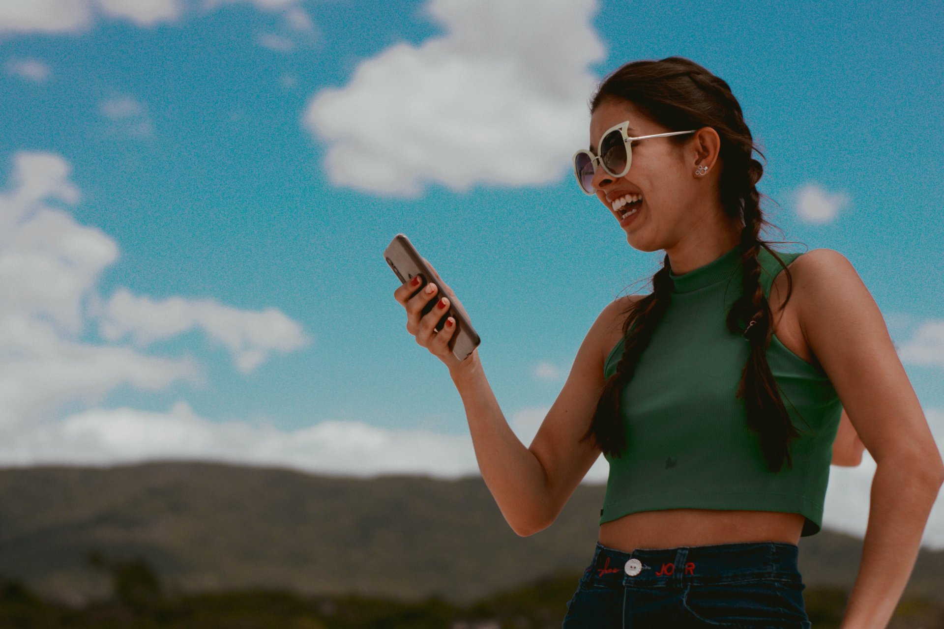 chica con gafas de sol sonriente usando su móvil con datos esim en el extranjero 