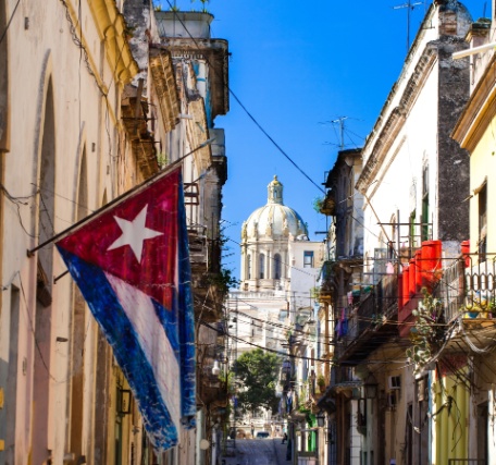 Bandera cubana ondeando en una calle de La Habana vieja con el Capitolio de fondo