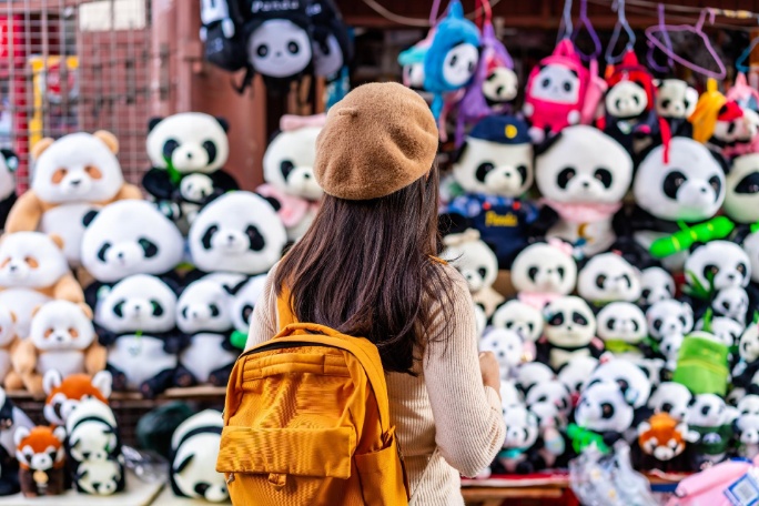 China, joven viajera comprando souvenir panda