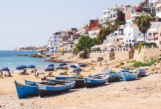 playa de taghazout con barcas y sombrillas en marruecos