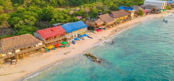Vista aérea de los chiringuitos y restaurantes con techos de paja y sombrillas coloridas en Playa Blanca de Isla Barú junto al mar turquesa