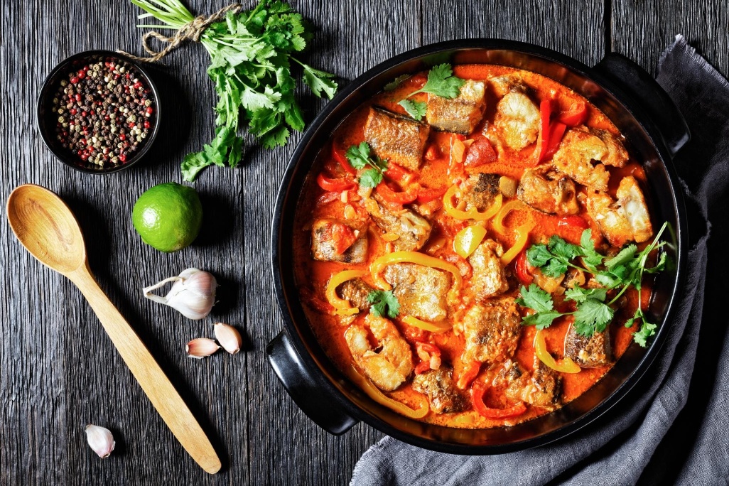 Moqueca baiana - servido en un plato negro con cilantro sobre fondo de madera oscura, vista superior