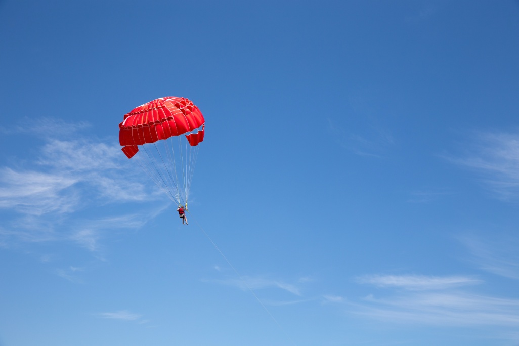 Hombre haciendo parasailing con paracaídas rojo