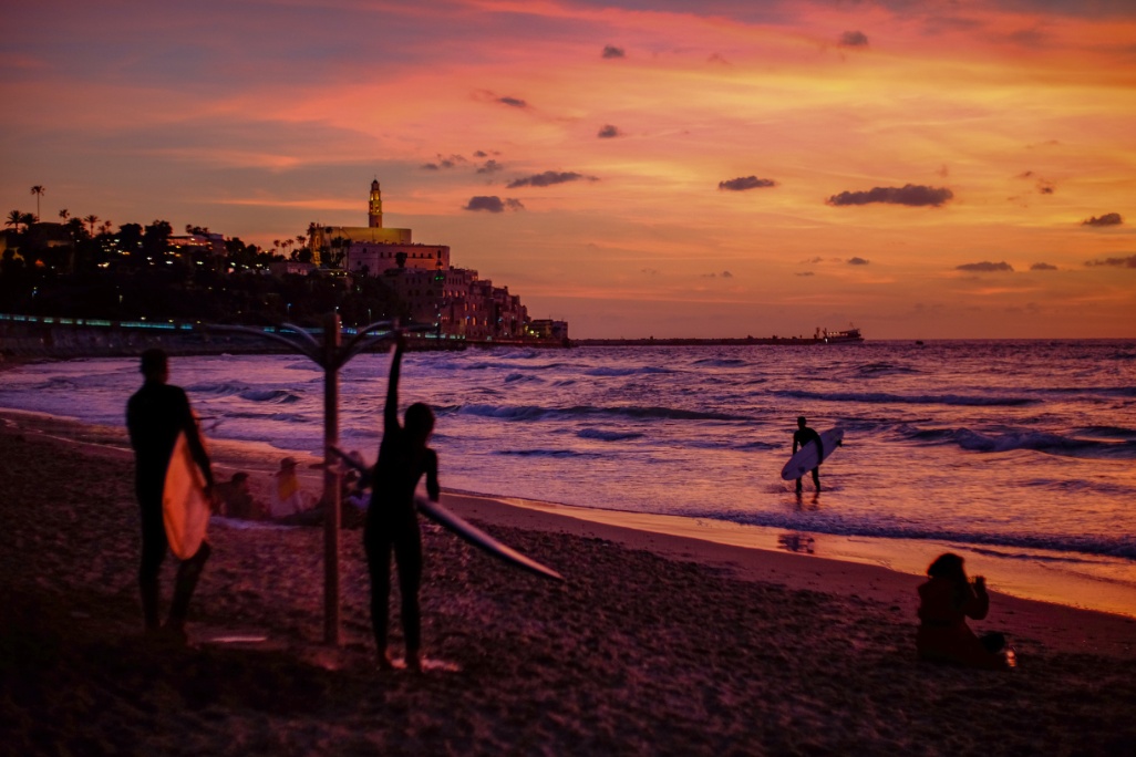 puesta de sol en playa tel aviv con surfistas
