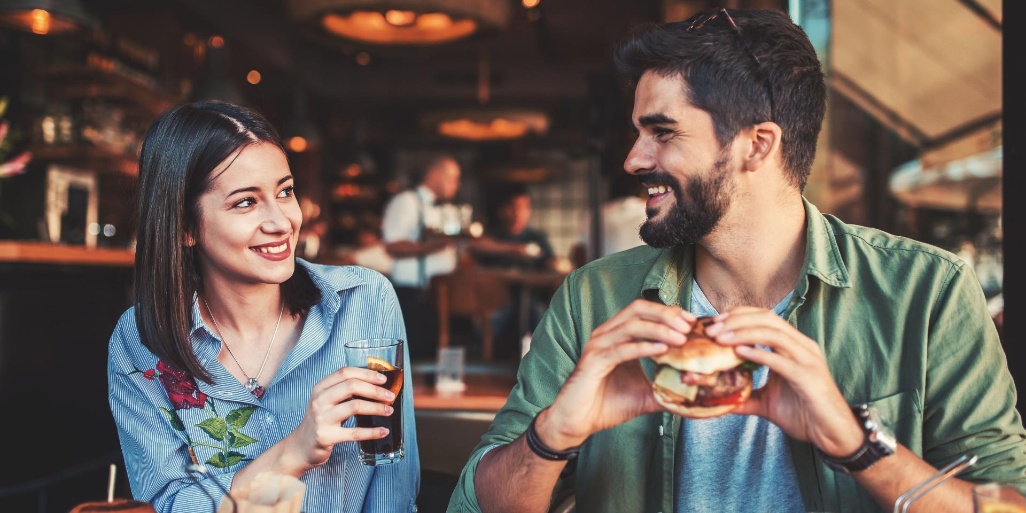 pareja brindando y comiendo hamburguesa en un restaurante