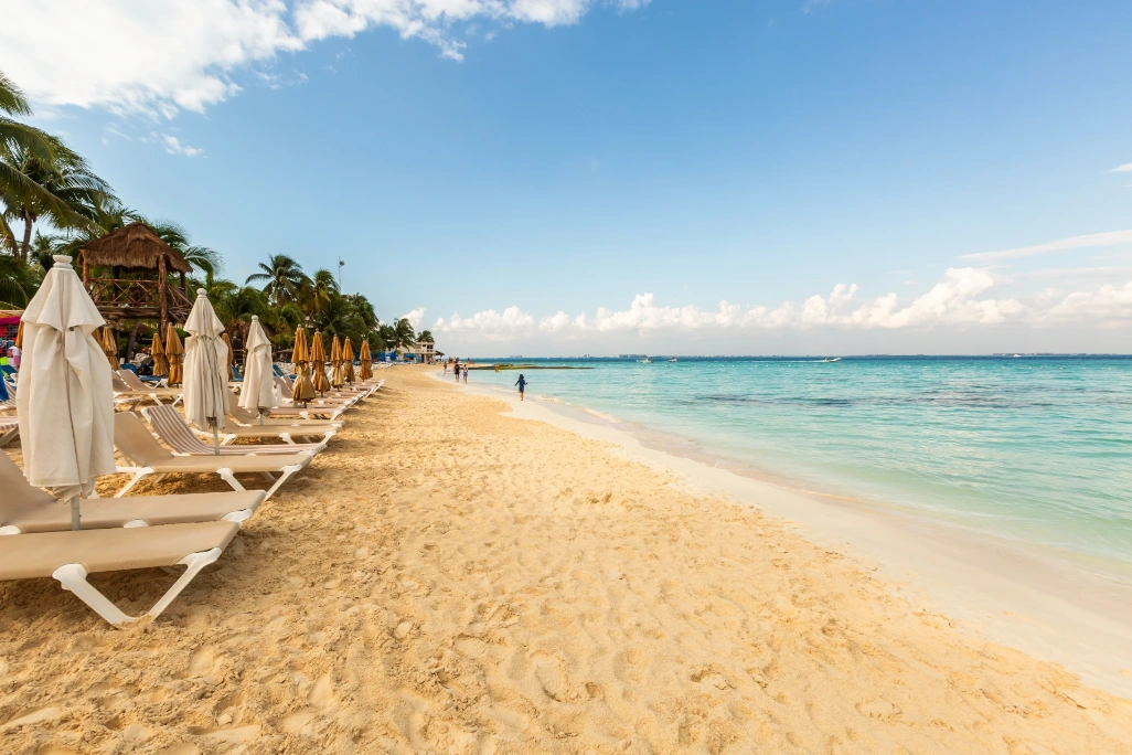 Costa Mujeres: playa tranquila de arena dorada con tumbonas, sombrillas y palapa, el rincón del Caribe mexicano perfecto para desconectar