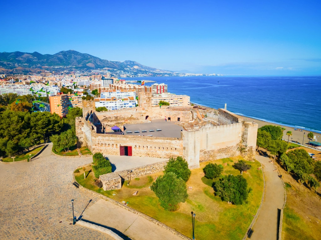 Vista panorámica de Fuengirola, en la Costa del Sol, con el Castillo de Sohail junto al mar, la playa urbana y las montañas al fondo