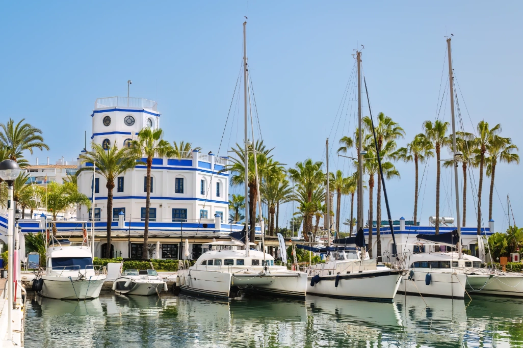 Embarcaciones amarradas en el puerto deportivo de Estepona, con palmeras y edificios blancos de estilo andaluz junto al mar