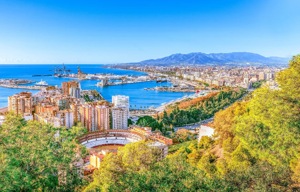 Vista panorámica de Málaga ciudad con el puerto, el paseo marítimo, la plaza de toros y las montañas al fondo