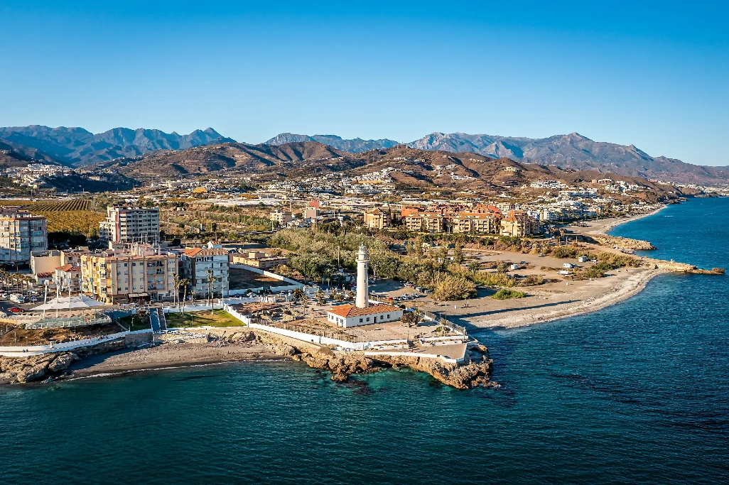 Vista aérea de Torrox Costa, en la Costa del Sol, con el faro, la playa, el paseo marítimo y las montañas al fondo