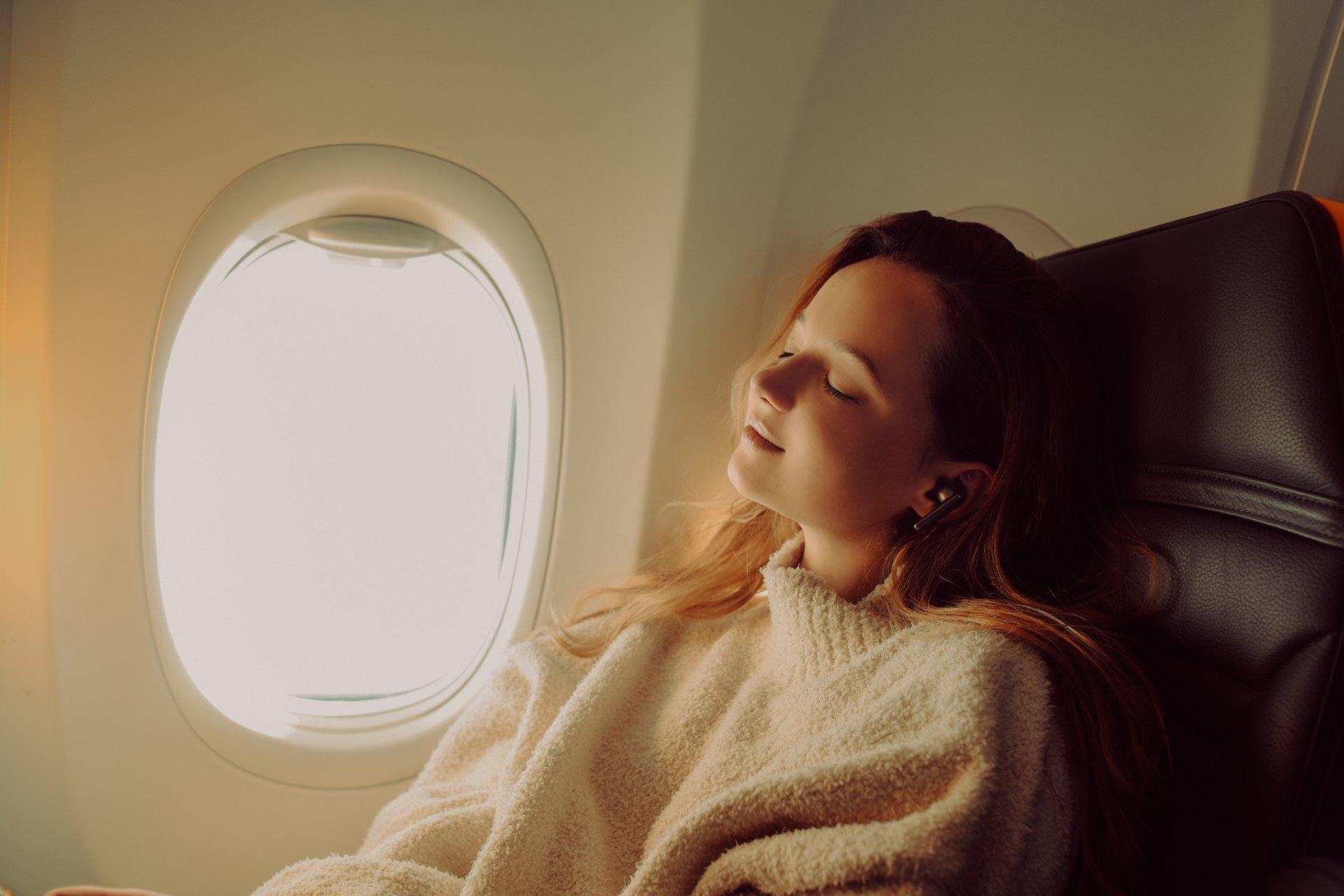 mujer pasajera de avión durmiendo plácidamente a bordo junto a ventanilla