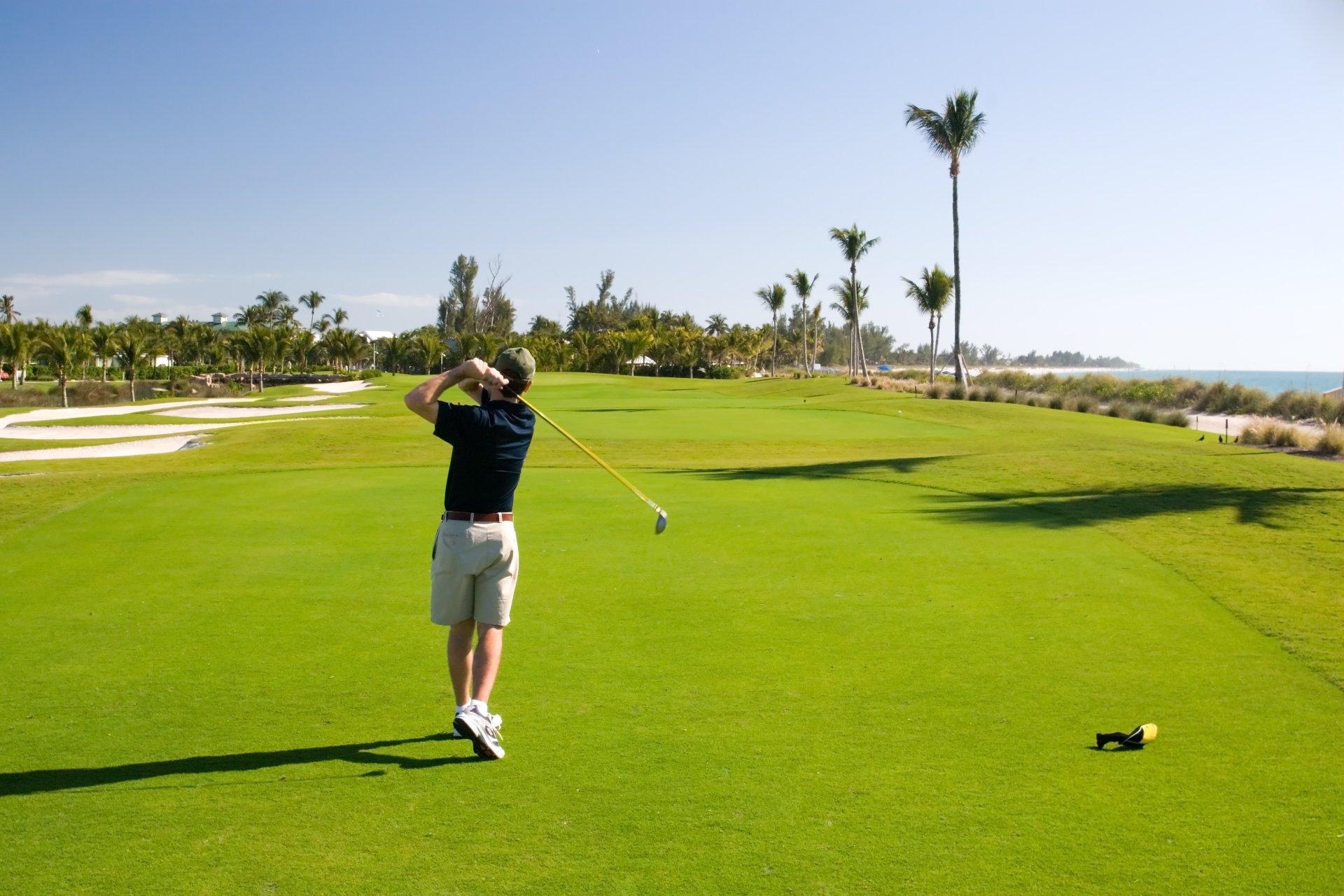 jugador de golf en campo junto al mar Caribe con palmeras