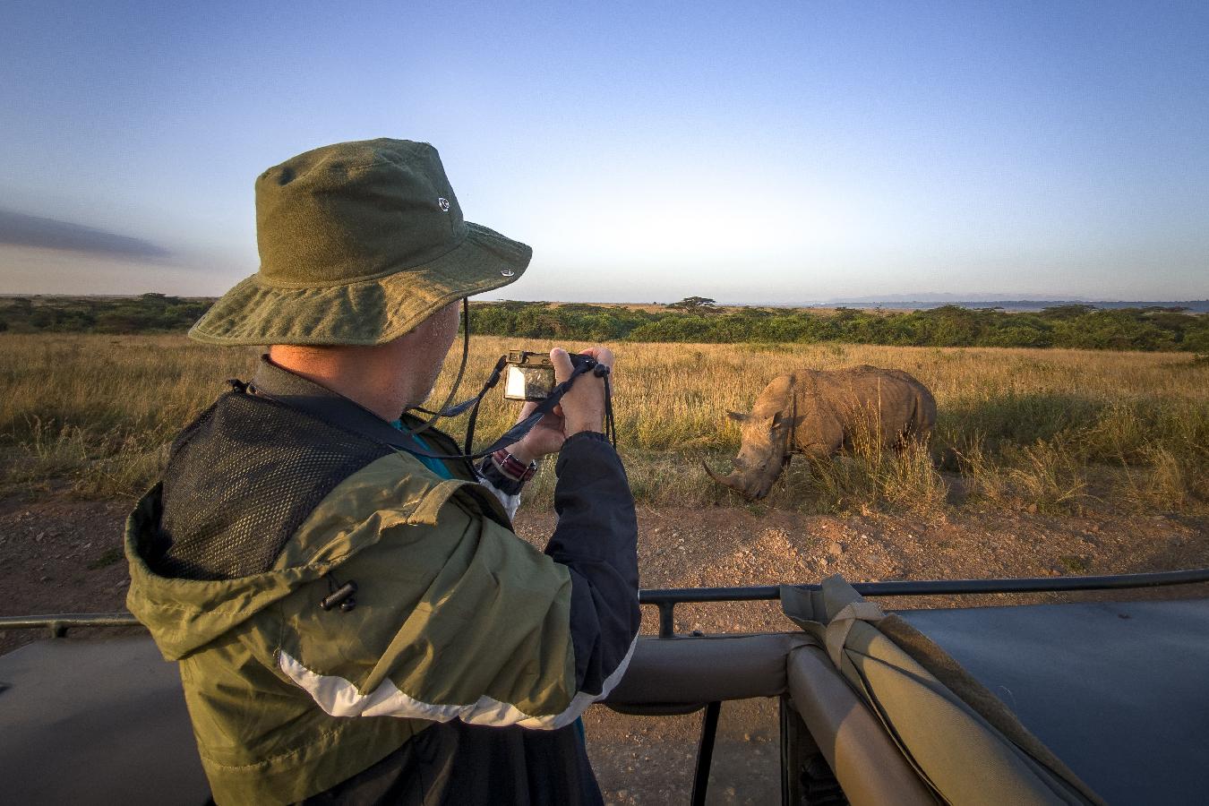 Un turista fotografía a un rinoceronte durante un recorrido de safari en Kenia