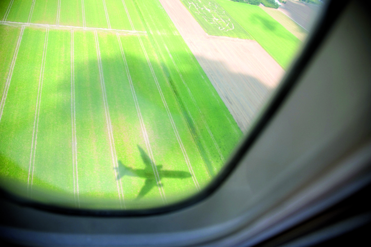 Sombra de avión en un campo verde vista desde la ventana de un avión