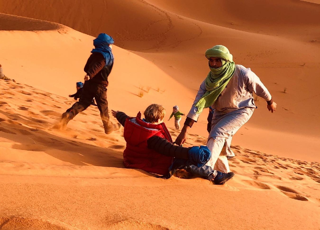 Niño deslizandose en las dunas del desierto