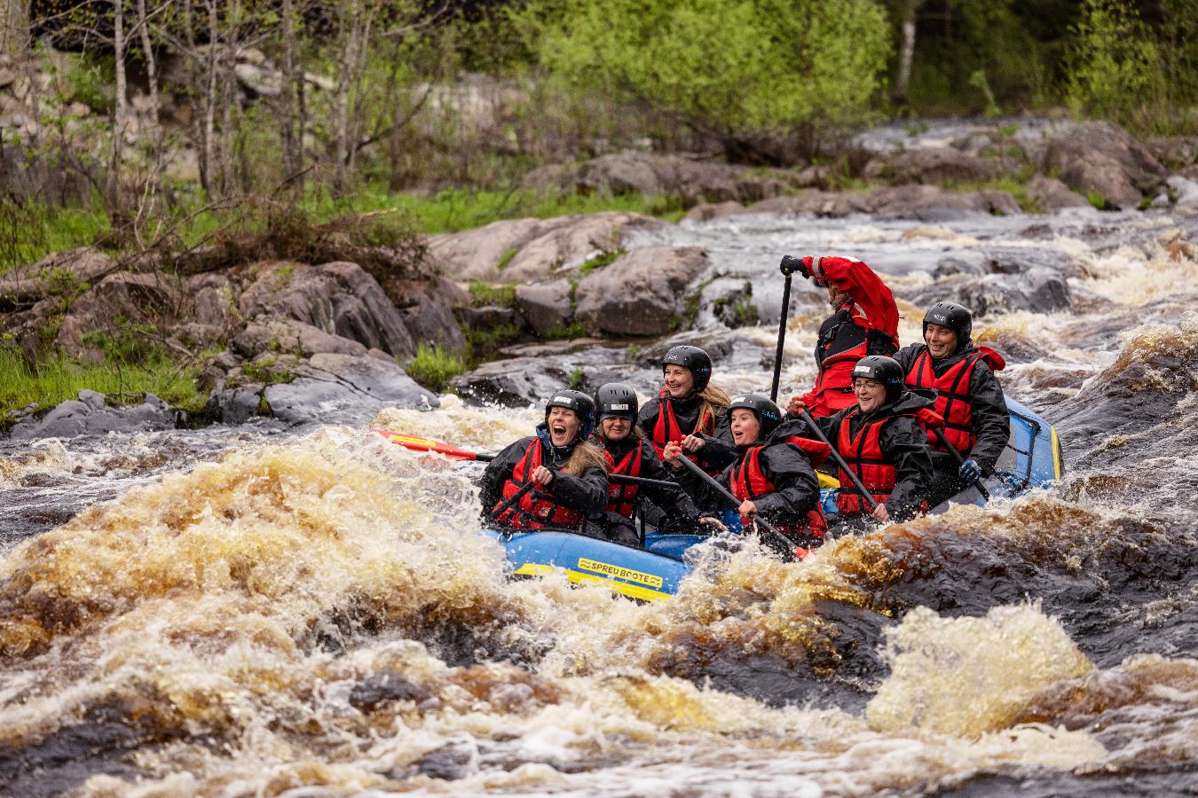 Grupo de jóvenes practicando rafting en los rápidos de Koiteli
