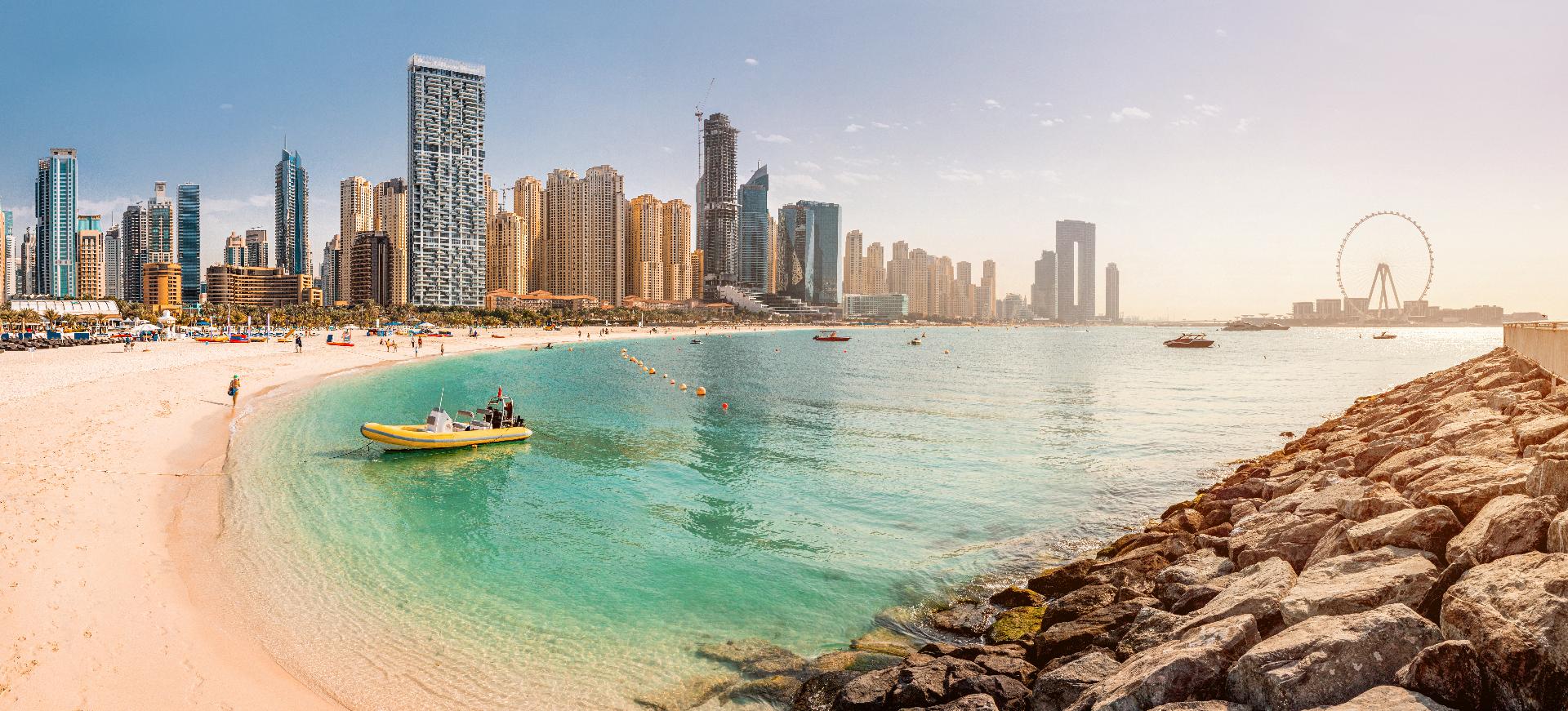 Playa de arena y aguas azules con la famosa Dubai Eye y numerosos rascacielos con hoteles