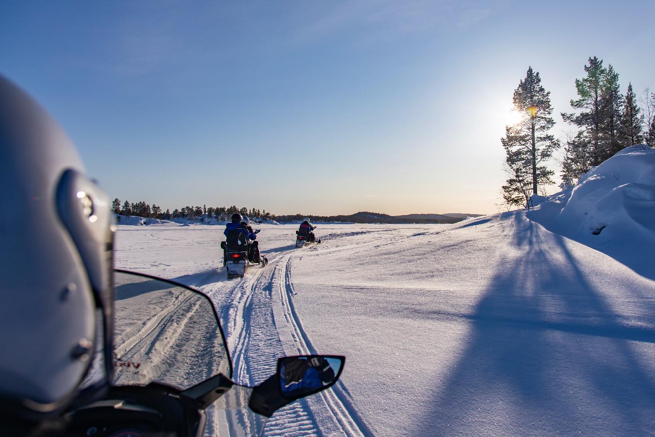 Tour turístico en moto de nieve por un lago helado en Laponia