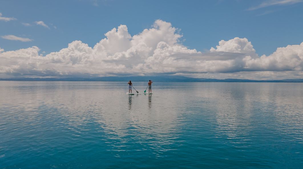 Pareja practicando padel surf en aguas de un mar de Costa Rica